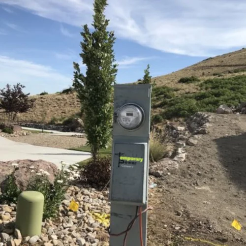 TCS temporary power pedestal installed near a graded Utah residential lot