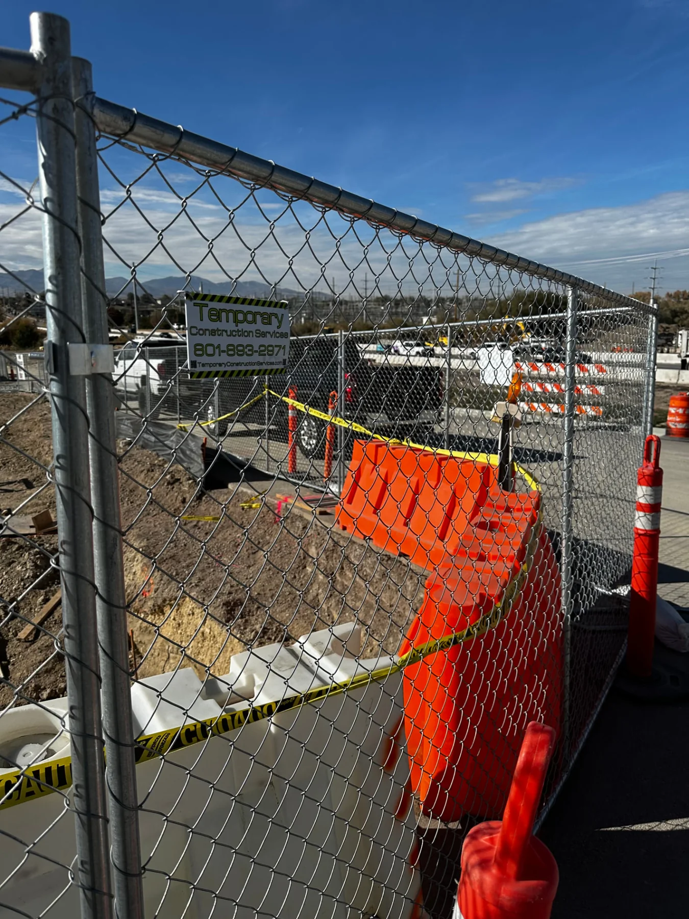 TCS chain-link construction fence separating an active excavation from a public walkway