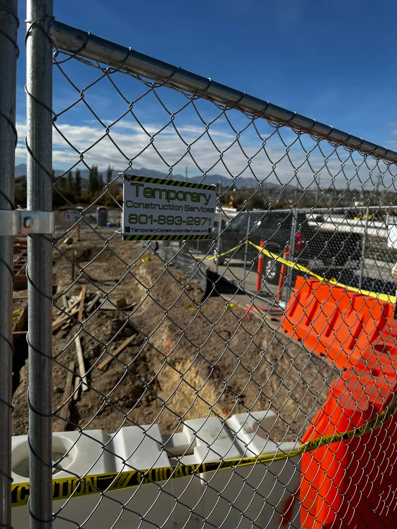 TCS construction fence beside trench work, traffic barriers, and marked site access