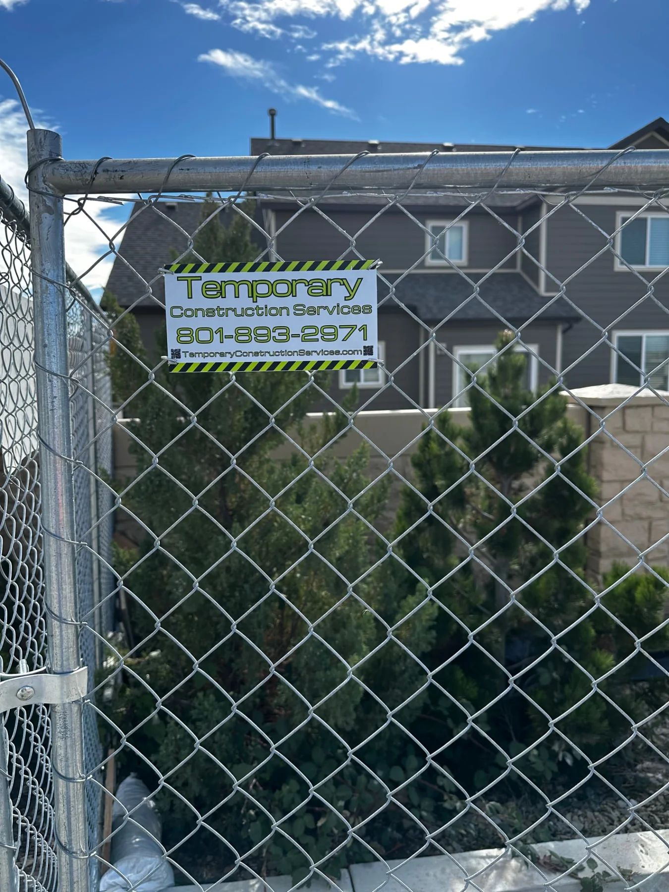 TCS temporary chain-link fence and branded sign at a residential construction site